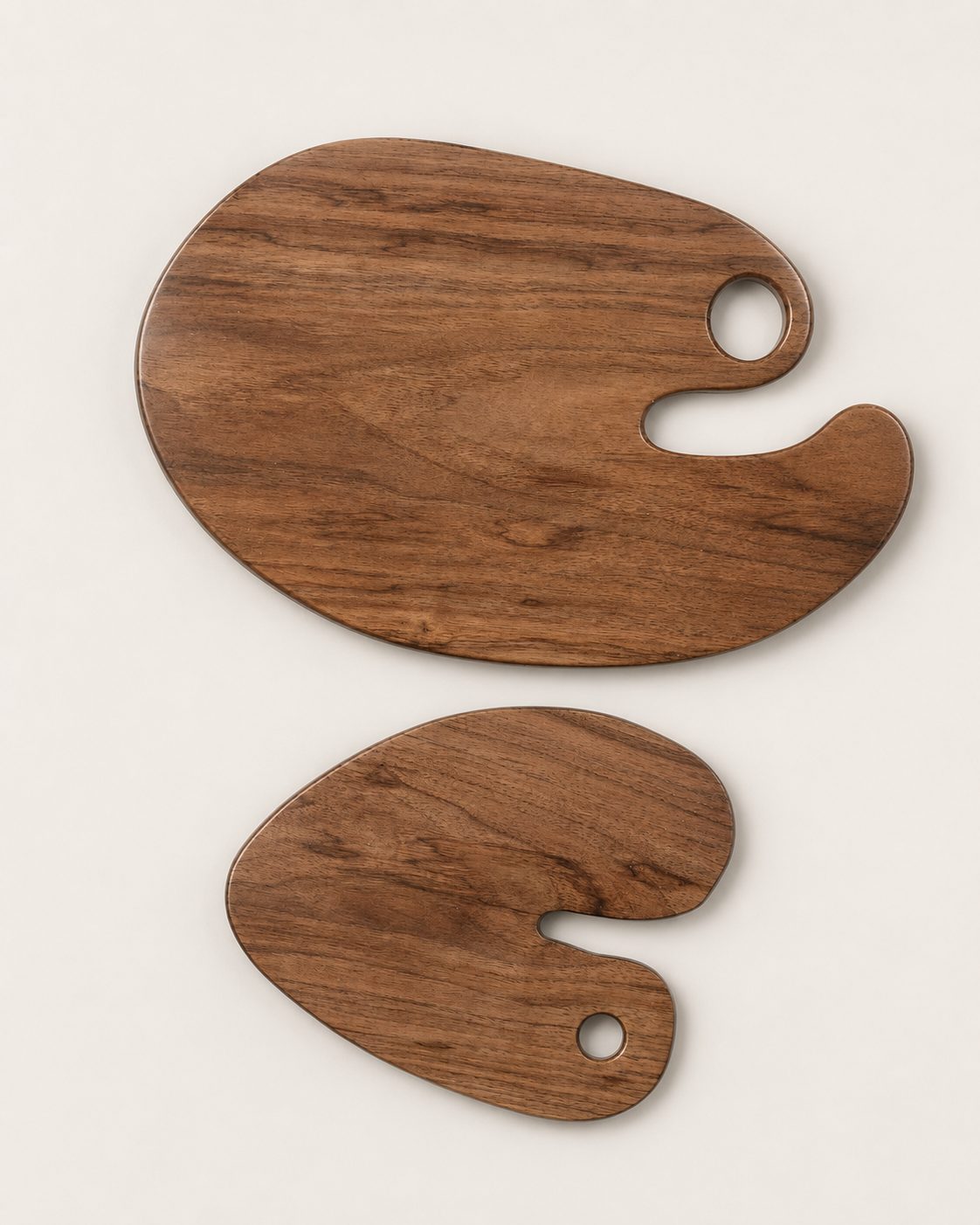 Two walnut serving boards shaped like artist palettes with thumb holes