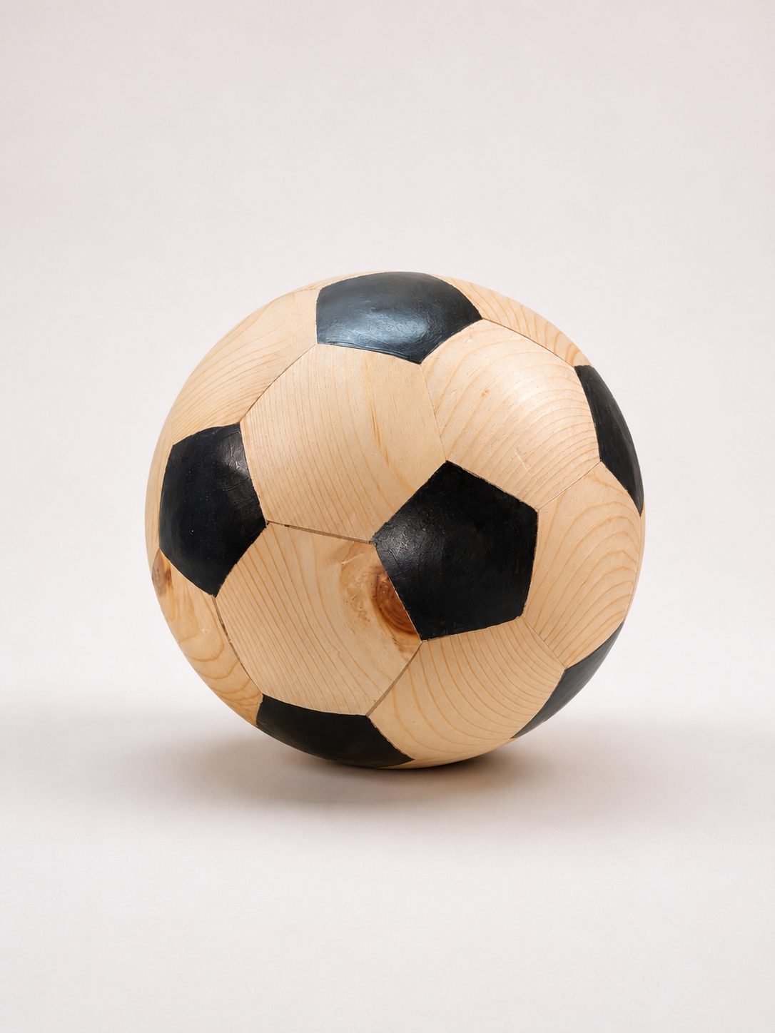 Handcrafted wooden soccer ball made of 32 pentagon and hexagon panels in pale wood and black
